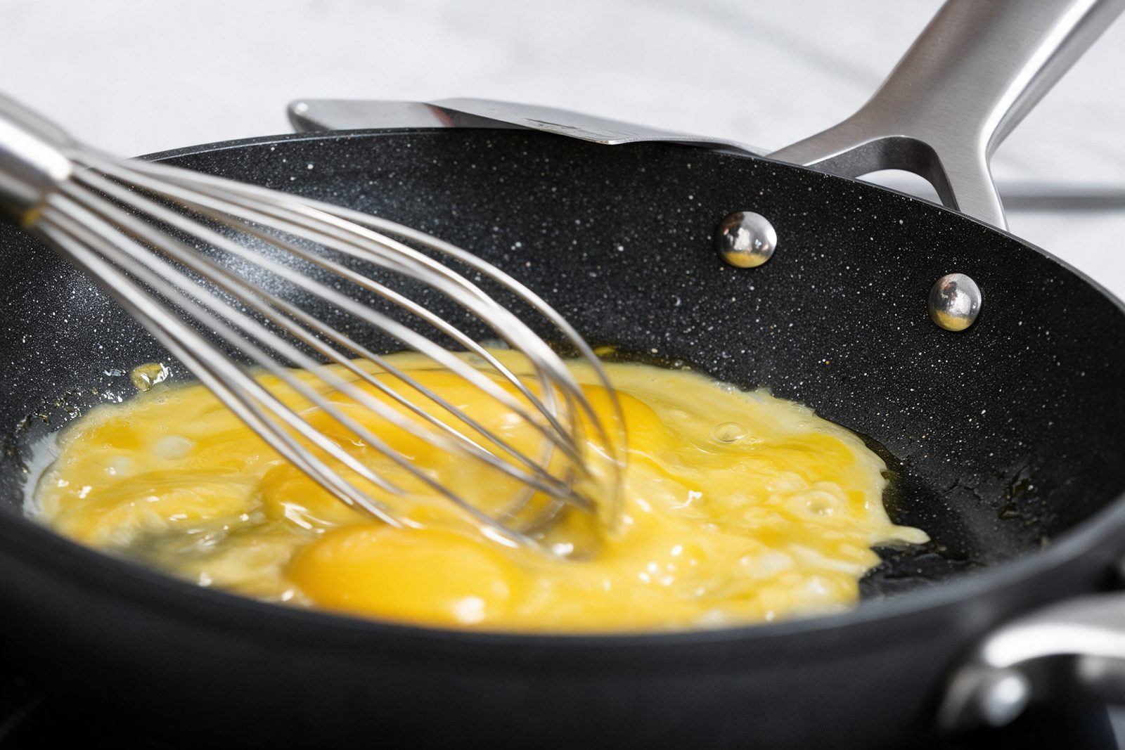 A metal whisk in an Armor Max pan